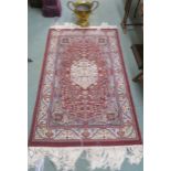 A modern burgundy ground wool rug with cream central medallion and border, 160cm x 97cm and a