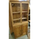 A pine two door glazed cabinet with shelves on an associated two door base, 169cm high x 79cm wide x