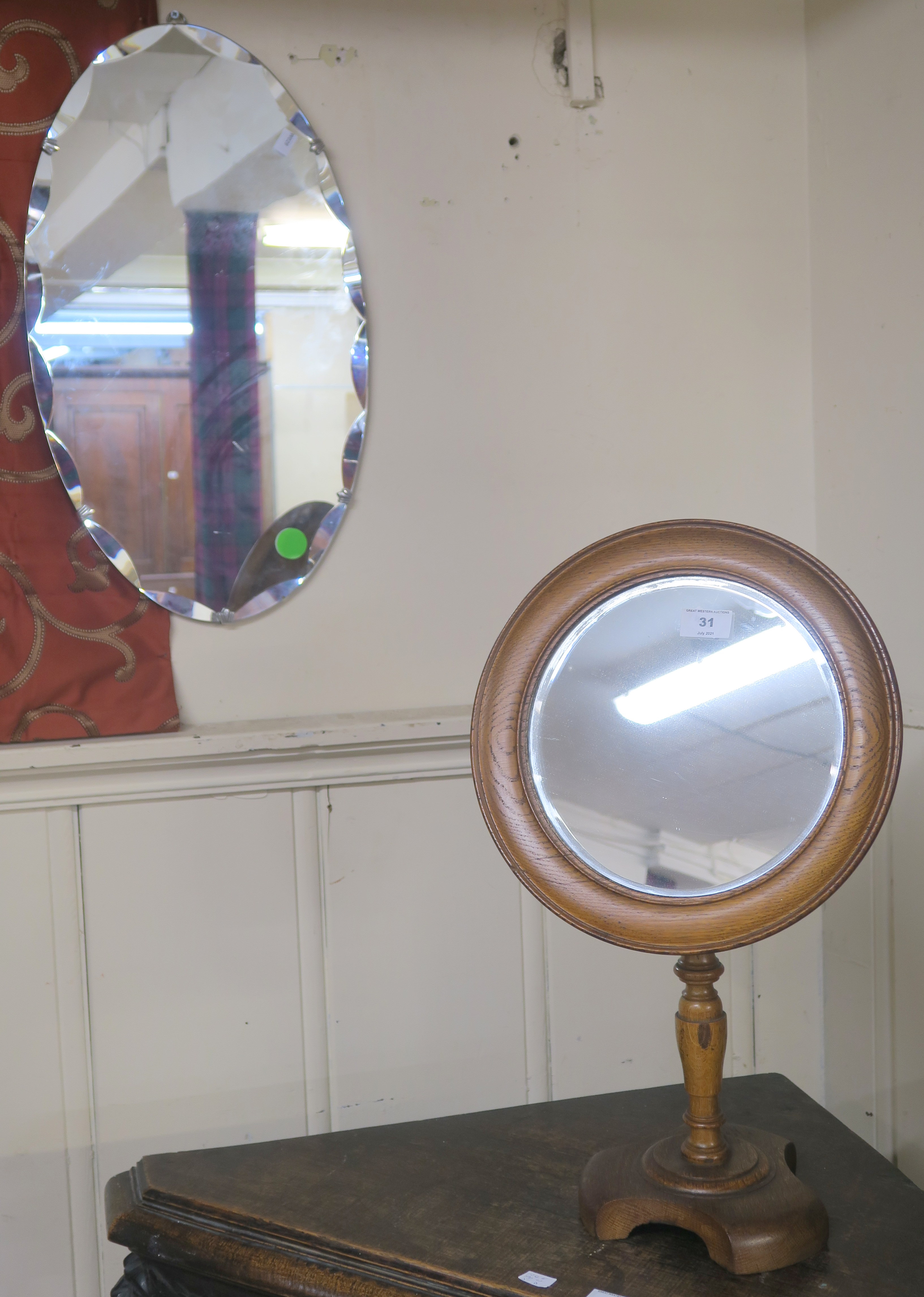 A circular tilting mirror on turned support on shaped base, 55cm high x 33cm diameter and a