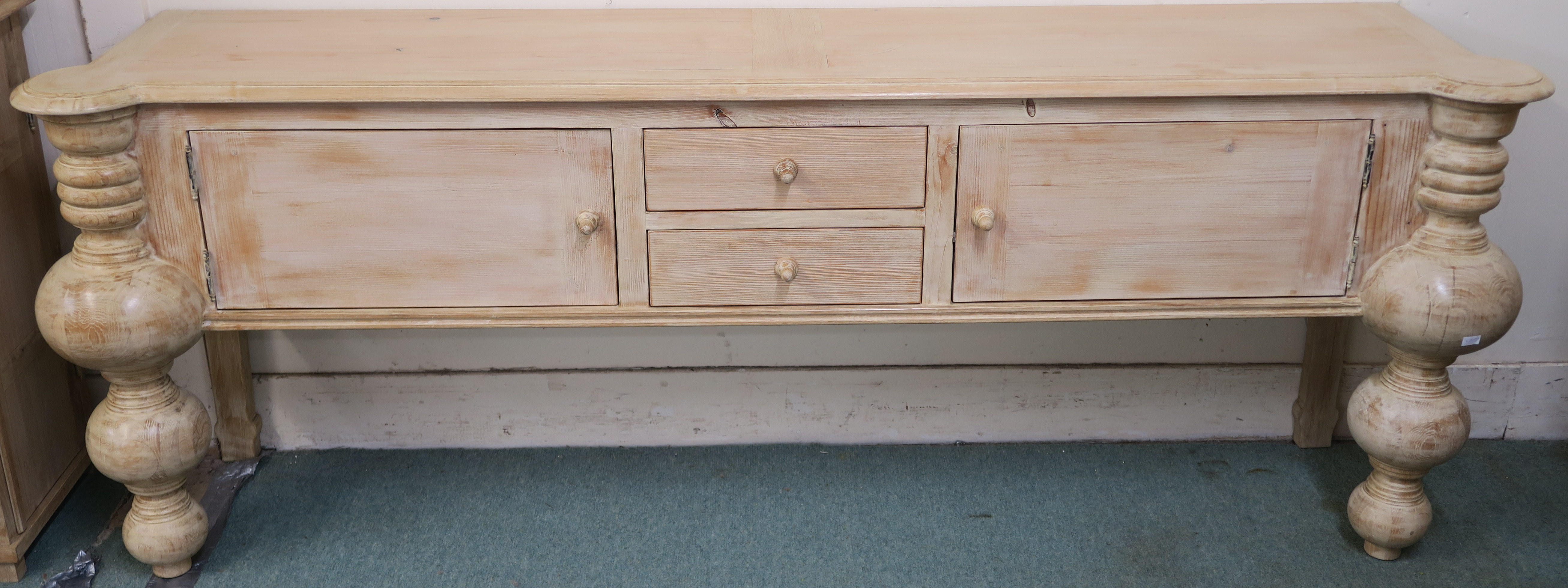 A modern limed pine console table with two drawers flanked by two doors with baluster shaped