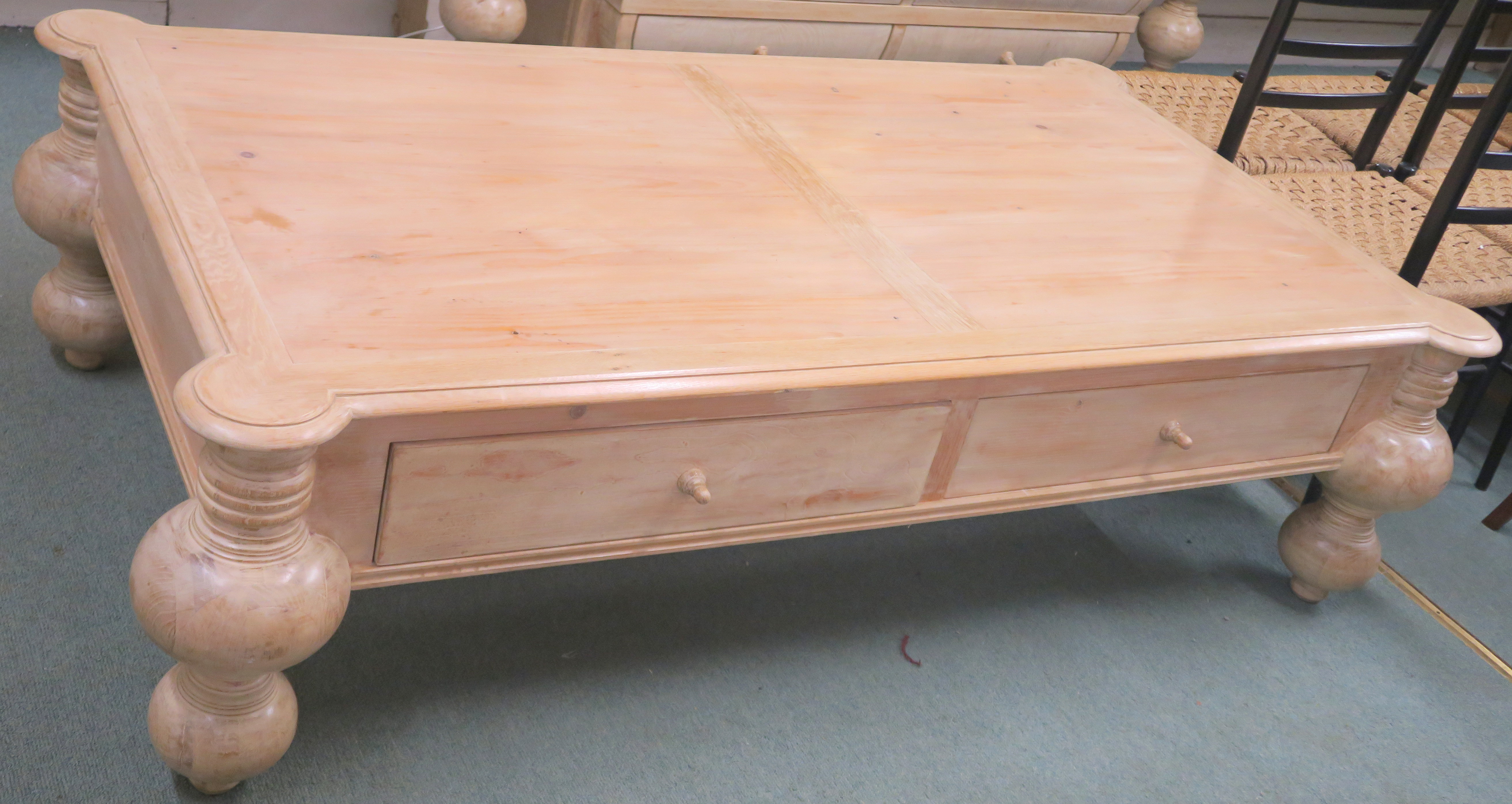 A modern limed pine coffee table with four drawers on baluster supports, retailed by Design Works,