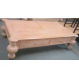 A modern limed pine coffee table with four drawers on baluster supports, retailed by Design Works,