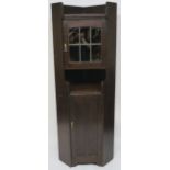 A Liberty & Co oak corner cabinet, the upper section having leaded glazed door over open shelf on