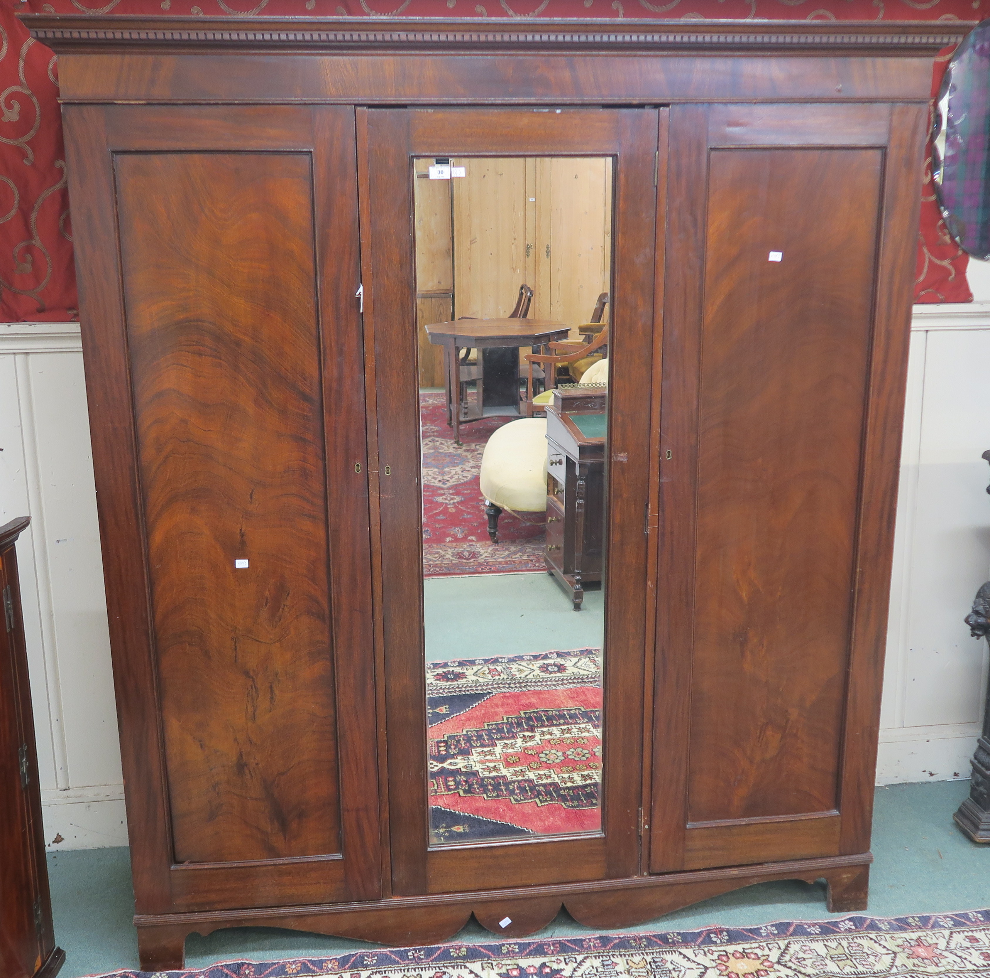 A triple mahogany wardrobe with dentil crown over mirror door flanked by two doors, 195cm high x