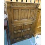 An oak cocktail cabinet with linen fold drop front over two doors, 121cm high x 80cm wide x 48cm