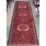 A red ground Karajeh runner with central lozenges, geometric designs and stylised animals, 315cm x