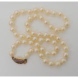 A string of pearls with a 9ct gold purple gem set clasp, length 45cm, weight 25.5gms Condition