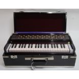A cased bellows harmonium with a collection of Gaelic Song and Scottish Violin printed music etc