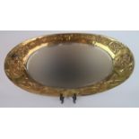 A GLASGOW SCHOOL OF ARTS AND CRAFTS BRASS FRAMED MIRROR of oval form with celtic knotwork