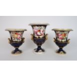 A GARNITURE OF COALPORT STYLE TWO HANDLED URNS each painted with panels of flowers surrounded by