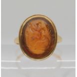 A BRIGHT YELLOW METAL INTAGLIO RING set with a carved yellow hardstone (probably citrine), depicting