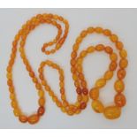 TWO STRINGS OF AMBER BEADS the longest strand is 64cm, the largest bead measures 22mm x 17.3mm,