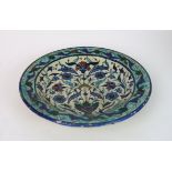 A PERSIAN POLYCHROME DISH painted with flowers issuing from and surrounding an urn, within a