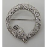 A HICKLENTON & SYDAL ART DECO DIAMOND BROOCH the pierced white metal circlet with draped floral form