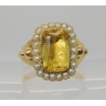 A BRIGHT YELLOW METAL REGENCY STYLE RING set with split pearls and a yellow glass gem in a closed
