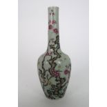 A CHINESE CELADON GROUND BOTTLE VASE painted with blossoming branches on gnarled trees, 21cm high