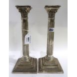 A pair of silver Corinthian column candlesticks with reeded stems on stepped and beaded bases,