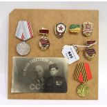 A mounted collection of Russian medals and enamel badges & a postcard Condition Report: Available