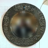 An Arts & Crafts style pewter circular wall mirror with repousse floral decoration & inlaid