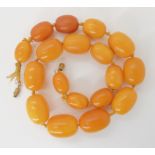 A STRING OF YELLOW AMBER BEADS largest bead 26mm x 18.5mm, smallest bead, 18mm x 13.2mm. Length