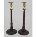 A PAIR OF MAHOGANY AND BRASS MOUNTED CANDLE STICKS with turned stems and circular bases, 39cm high