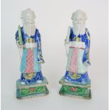 A PAIR OF CHINESE EXPORT MODELS OF OFFICIALS each standing and holding a scroll, diaper aprons and