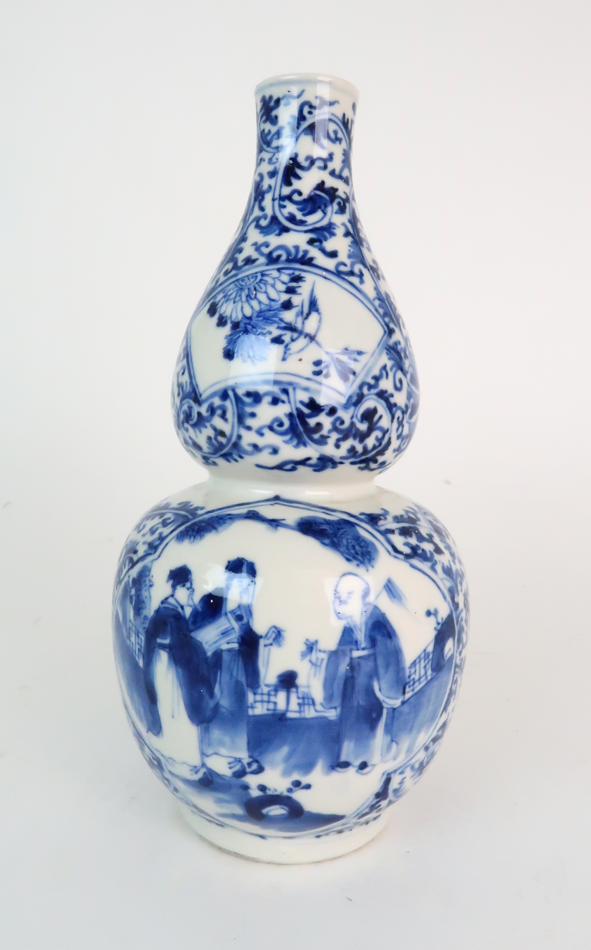 A CHINESE BLUE AND WHITE DOUBLE GOURD SHAPED VASE painted with panels of figures in conversation