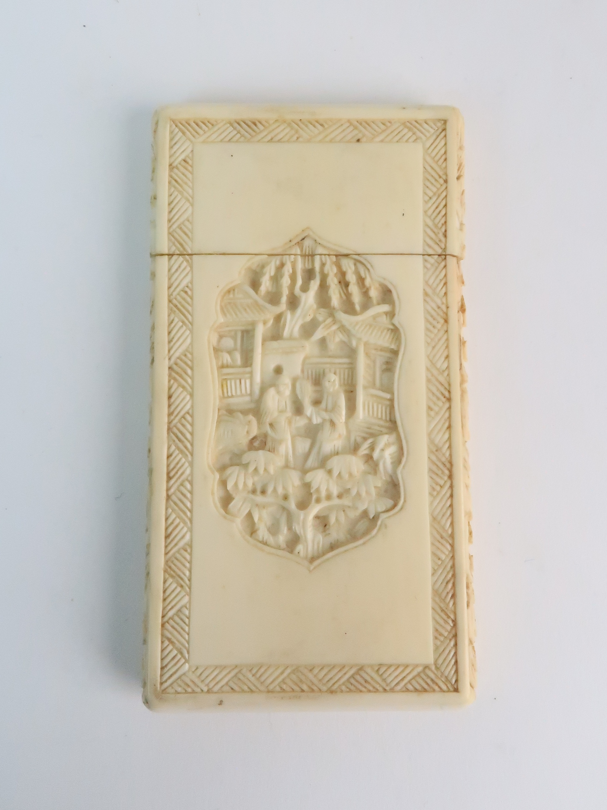 A CANTON IVORY CARD CASE carved with a vignette with figures in a village the reverse with a cross