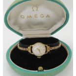 A 9CT GOLD LADIES VINTAGE OMEGA WRISTWATCH with a cream dial with gold coloured Arabic and chevron