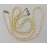 TWO STRINGS OF PEARLS WITH DECORATIVE CLASPS a string of cream pearls with good lustre, with a