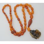 A STRING OF AMBER BEADS WITH A CHINESE CARVED PENDANT the agate pendant is carved with a bat, bee