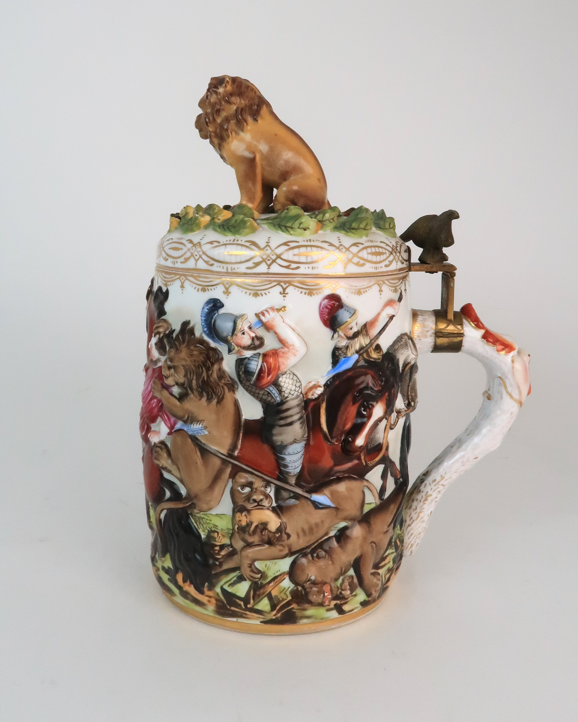 AN EARLY 20TH CENTURY HEREND TANKARD moulded and painted in relief with a battle scene, with brass