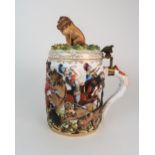 AN EARLY 20TH CENTURY HEREND TANKARD moulded and painted in relief with a battle scene, with brass