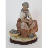 A LARGE LLADRO FIGURE OF A SITTING GIRL with a set of scales and fish at her feet, 36cm high