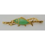 A 22CT GOLD GREEN HARDSTONE FISH BROOCH depicting a fish among pond weeds, length 5cm x 1.2cm,