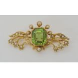 A 15CT GOLD PERIDOT AND PEARL EDWARDIAN BROOCH depicting lily of the valley, the peridot is