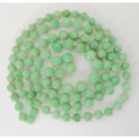 A LONG STRING OF CHINESE GREEN HARDSTONE BEADS largest bead 10.8mm, smallest 7mm, a continuous