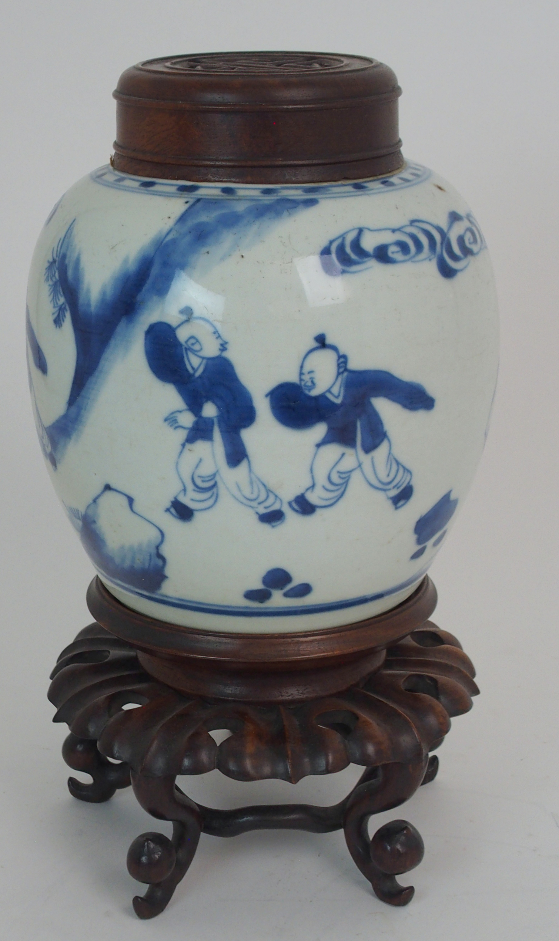 A CHINESE BLUE AND WHITE GINGER JAR painted with children at play, 15.5cm high, wood stand and cover
