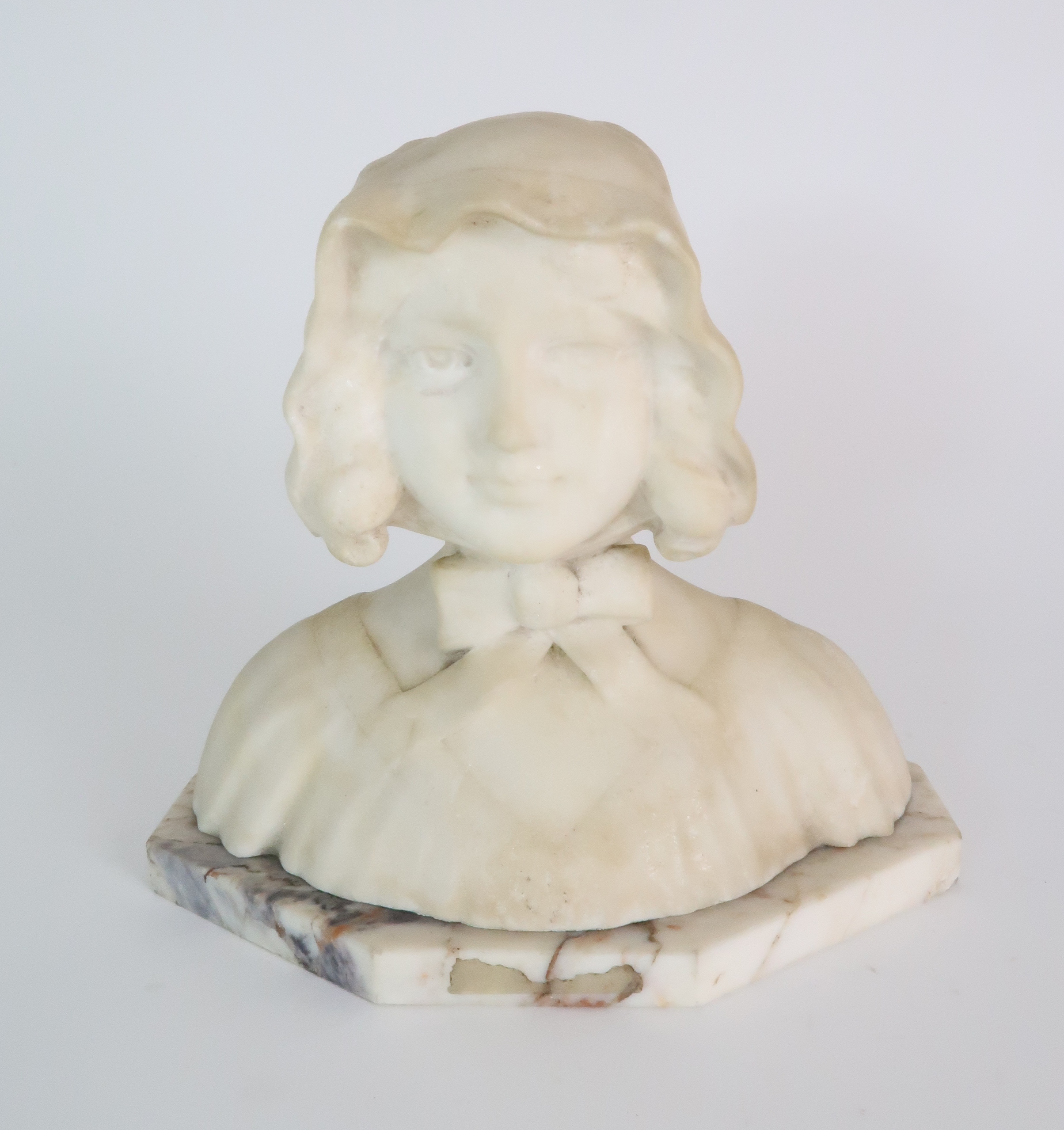 AN ALABASTER BUST OF A GIRL IN A BONNET upon onyx base, 20cm high Condition Report: Available upon