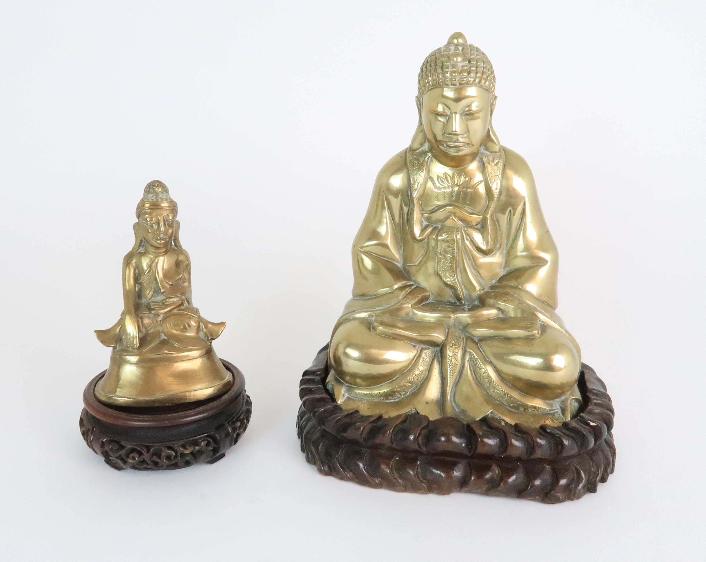 AN ASIAN BRASS MODEL OF BUDDHA seated in the lotus position and with carved wood base, 24.5cm