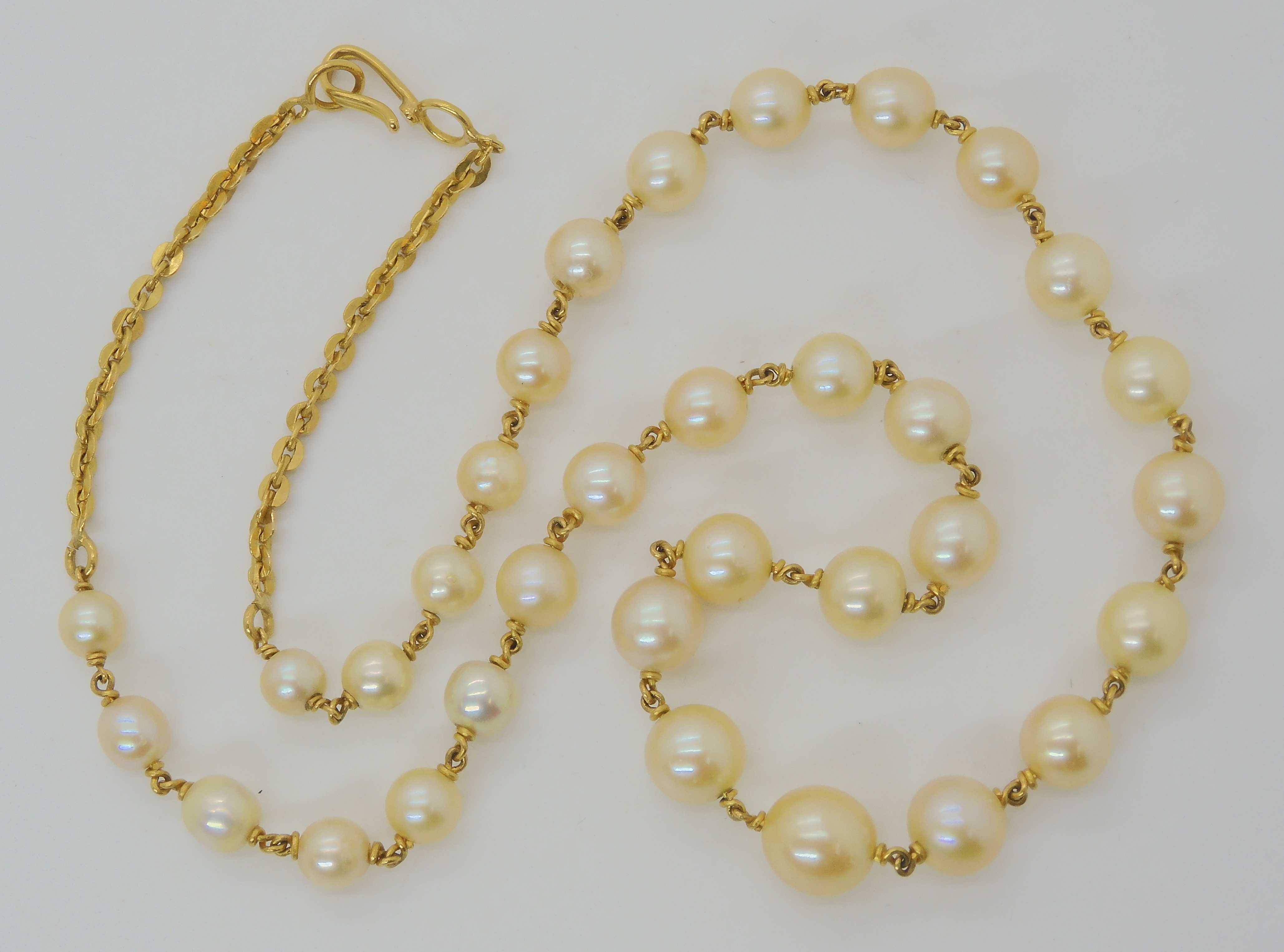 A YELLOW METAL LINKED PEARL NECKLACE largest pearl 9mm, smallest 5.6mm, length of necklace 49cm,