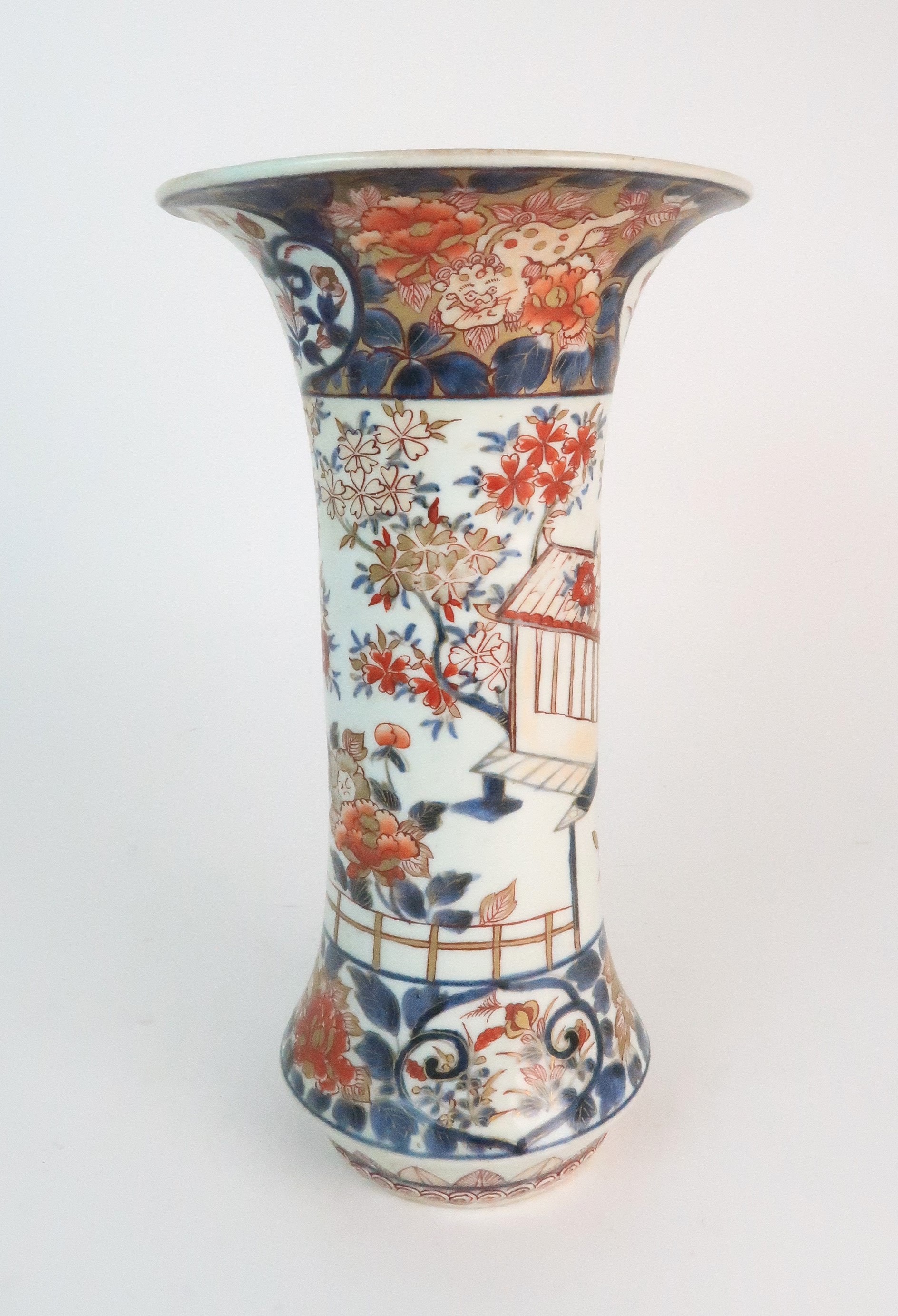 A JAPANESE IMARI FLARED CYLINDRICAL VASE painted with a building on stilts amongst flowering