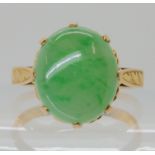 A 14K CHINESE GREEN HARDSTONE RING with engraved shoulders and heart pattern basket, approx