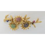 AN ITALIAN 18K GOLD FLOWER BROOCH set with rubies, sapphire and emeralds. Length 5.6cm, weight 10.