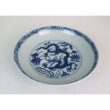 A CHINESE BLUE AND WHITE DISH painted with dragons amongst aquatic foliage, within a scrolling