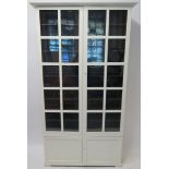 AN ARTS AND CRAFTS STYLE WHITE PAINTED DISPLAY CABINET with overhanging cornice above a pair