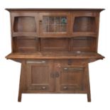 A LIBERTYS OF LONDON OAK ARTS AND CRAFTS SIDEBOARD the overhanging cornice above a leaded glass