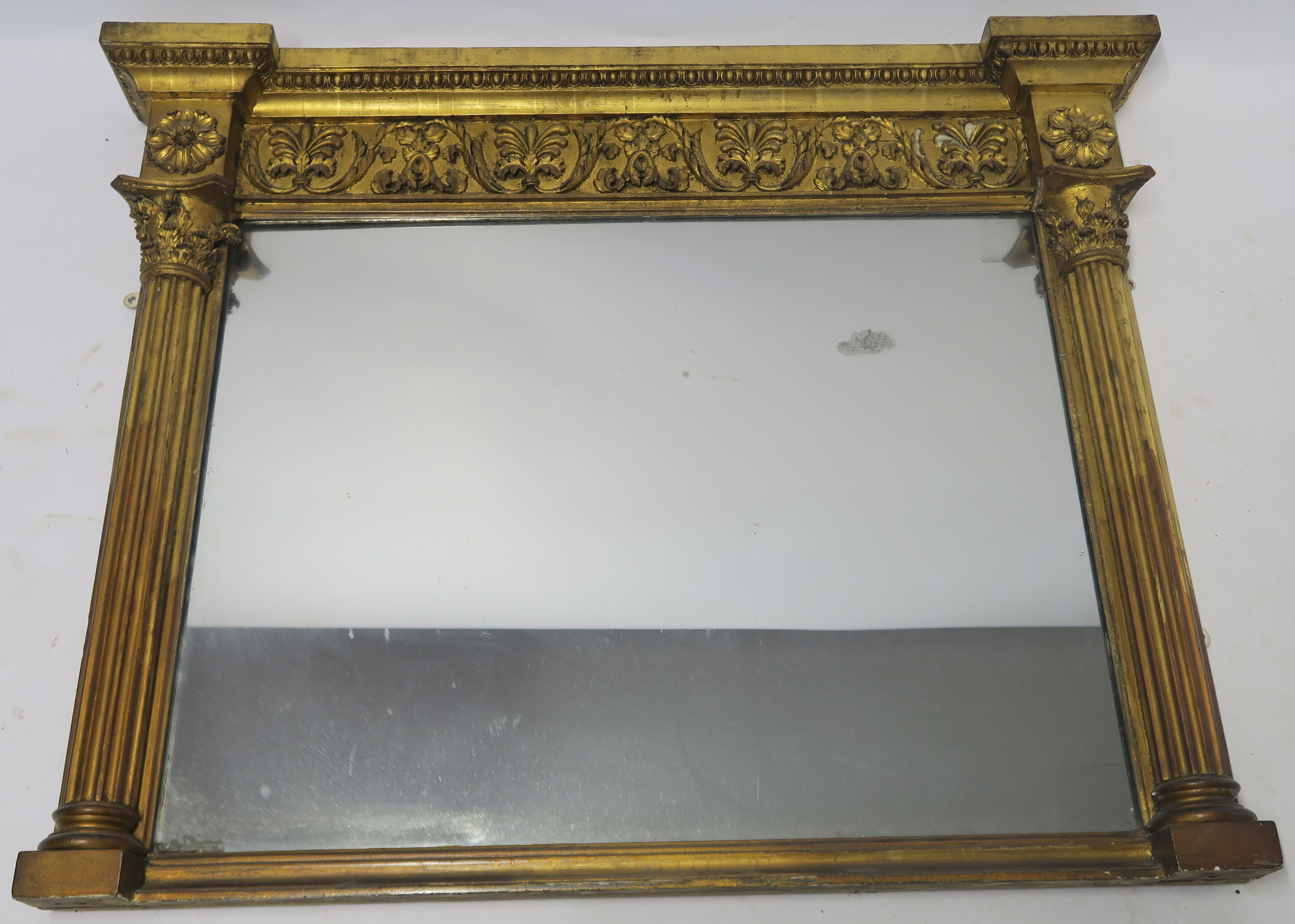 A REGENCY GILTWOOD OVERMANTLE MIRROR the cornice set with egg and dart moulding, above acanthus leaf