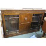 An oak bookcase with central panel flanked by two glazed doors, 115cm high x 172cm wide x 33cm