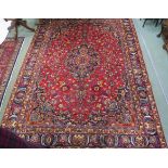 A red ground Mashad rug with blue central medallion, spandrels and borders, 330cm x 240cm